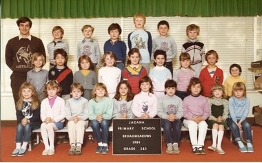 Formal class photo, with three rows of children, and an adult standing in the back row far left