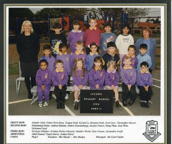 Children in 3 rows with adults on either side, playground is in background