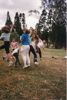 Children in a bunch, Jumping for the football with trees in the background
