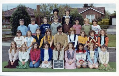 Formal Class Photograph with children in four rows, the front row is kneeling. An adult is sitting centre of the second row. 