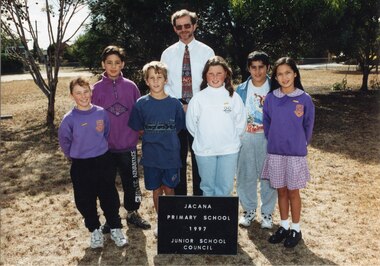 An Informal Group of six children in two rows with an adult in the centre of the second row, in front of trees