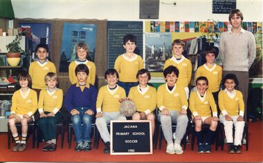 Formal Team Photograph of Children in two rows, the front rows seated. On the right is an adult standing just behind the child in the back row on the right. 