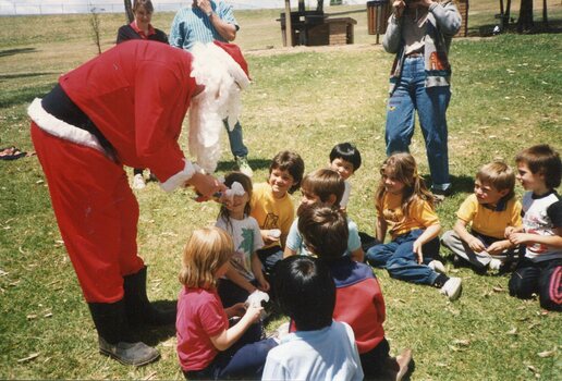 Father Christmas left with children sitting on the grass