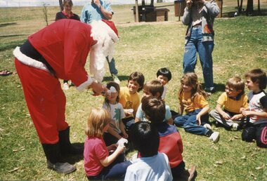 Father Christmas left with children sitting on the grass