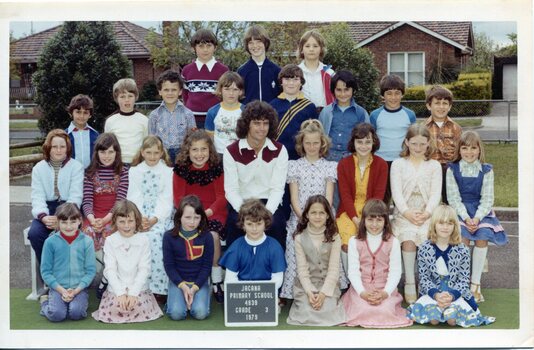 Formal class portrait with children in four rows the front row is kneeling. Centre of the second row is an adult sitting