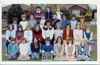 Formal class portrait with children in four rows the front row is kneeling. Centre of the second row is an adult sitting