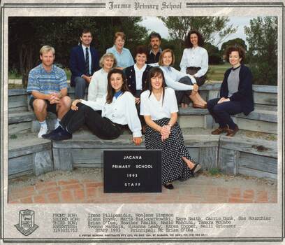 Semi-formal photograph of adults sitting in three rows on wooden benches