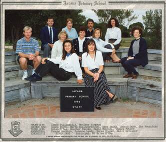 Semi-formal photograph of adults sitting in three rows on wooden benches