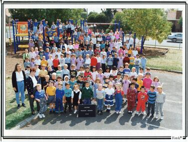 Formal school photograph of children and adults in front of a climbing frame