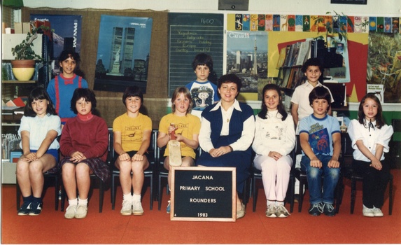Formal Team photograph of children in two rows, the back row is standing. Th child third from the right row is holding a bat.