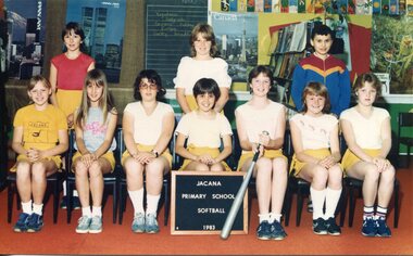 Formal Team photograph of children in two rows, the back row is standing. The child third from the right in the front row is holding a softball bat. 