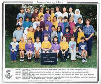 Formal School Photograph, of children in four rows, the front row is seated. To the second row is an adult, standing. In the background are trees. 