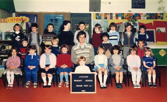 Formal photograph of children in three rows, the front row seated, in the centre of the front row is an adult seated