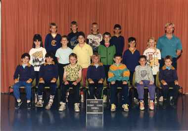Team photograph of children in three rows, with an adult standing in the third row on the right
