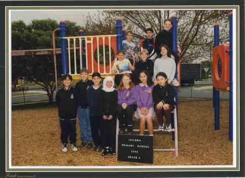 A Group of children posed on a climbing frame with a road and trees in the background 