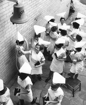 Nurse graduates ringing the ship's bell, Royal Children's Hospital, Parkville, 1968. Long shot of a group of Nurses ringing the bell after examinations are over.