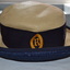 Cream coloured straw hat with blue ribbon band.  The band features a yellow gold school crest.
