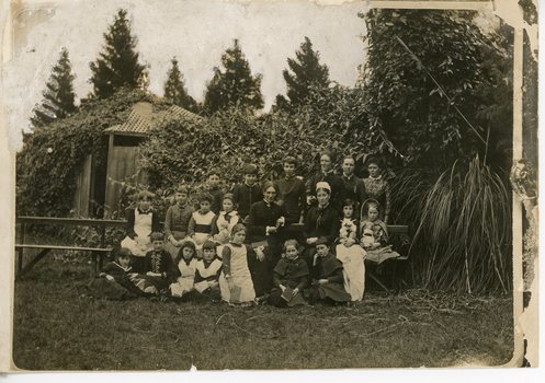 Black & white group photo of adult women and a group of children in a garden.