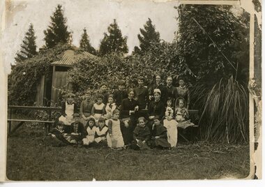 Black & white group photo of adult women and a group of children in a garden.