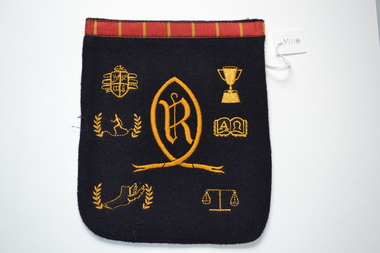 Navy blue wool blazer pocket with school crest and other symbols embroidered in yellow gold thread.