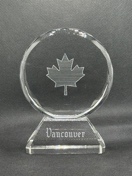 Front of circular glass award with engraving of maple leaf and text