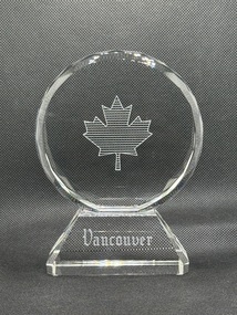 Front of circular glass award with engraving of maple leaf and text