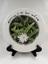 Front of ceramic plate with flower print and an inscription "Happiness is here & now"