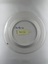 Back of ceramic plate with flower print and an inscription "Happiness is here & now"
