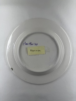 Back of ceramic plate with flower print and an inscription "Happiness is here & now"