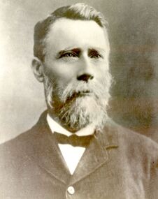 William has a neat pointed beard and moustache and hair parted on the right he is wearing a ribbon bow tie