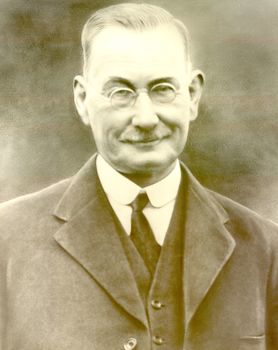 Black and white portrait of Mayor James Steele wearing steel rim glasses and three piece suit