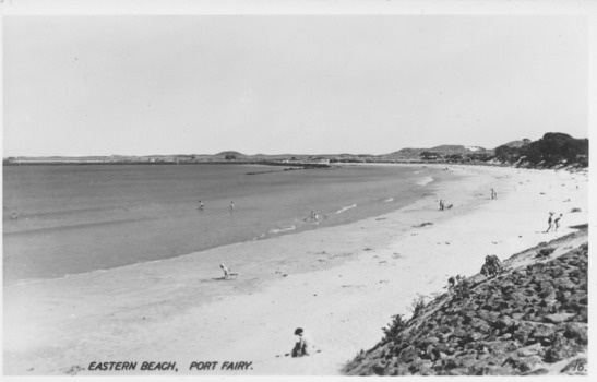 Curve of coastline at East Beach with scattered people 