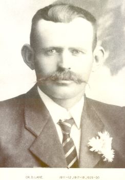Black and white portrait of Councillor D Lane with a flower in his left lapel