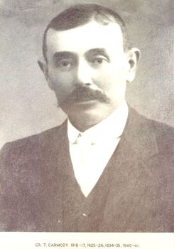 Black and white portrait of a male with a dark moustache and hair parted on the right