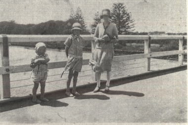 Two small children and mother standing on the Moyne river bridge with the botanical gardens in background