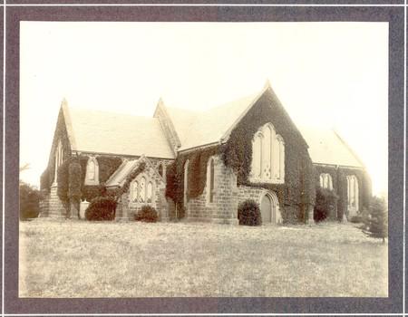 Black and white photograph of St Johns Church of England with ivy growing over the exterior 