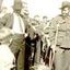 Group of men and boys surrounding a soldier in uniform on crutches