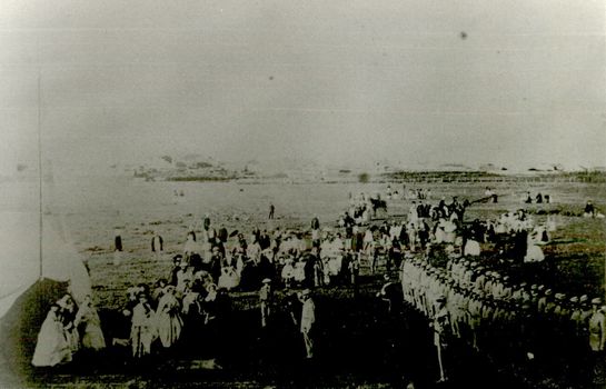 A group of people and soldiers gathered for a ceremony presenting a bugle