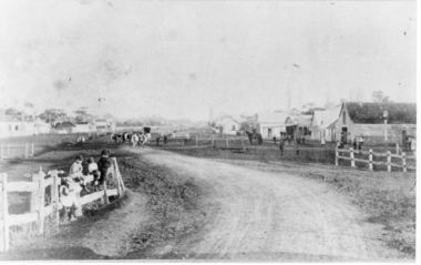 Post & rail fences children in foreground, buildings on right, cattle in far centre