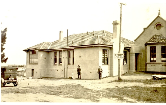 2 males standing at the corner of the new extension to the hospital