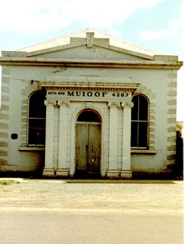 Imposing building with a faux columned portico, double door entry  two large windows either side