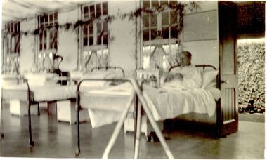 Interior of Ward 1B decorations above windows and male patient in nearest bed
