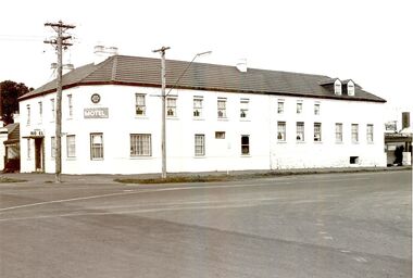 2 story building with multi paned windows power pole on corner and telegraph pole to the right