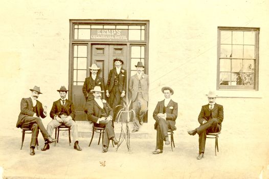 8 males outside the entrance to the Commercial hotel