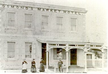 Two story market hotel with verandah over right side 3 females and a male on footpath
