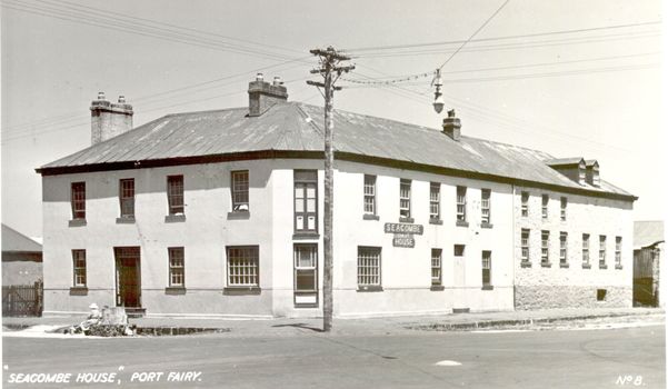 2 story rendered building with multi paned windows and power pole on corner