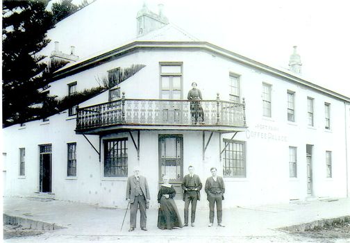 2 story building with a corner balcony 3 males and a female on footpath 1 female on balcony