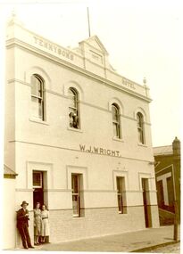 2 story building with tiled wainscoting male and 2 females in doorway and 2 females in window upstairs