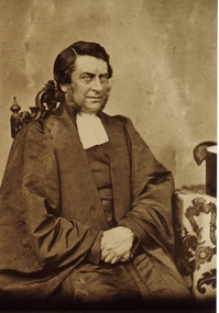 Sepia photograph of gentleman with large sideburns dressed in academic gown with white jabot 