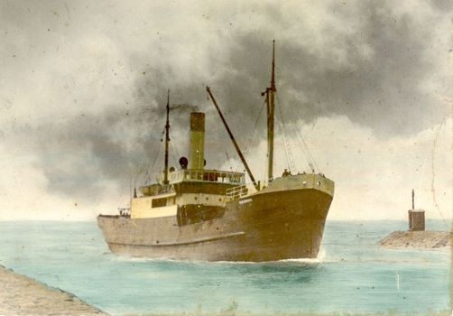 Ship surrounded by black smoke from her funnel, entering the entrance to the river Moyne with training walls Lo the left and right